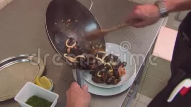 厨师用木刃从<strong>炒锅</strong>中放入准备好的贻贝、虾菜。 餐厅厨房。